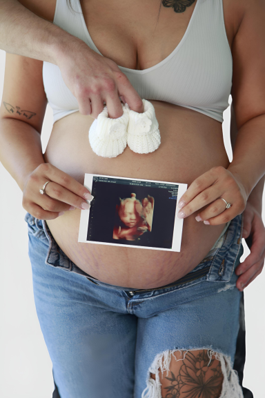 Pregnant belly with scan photo and booties. Maternity photoshoot