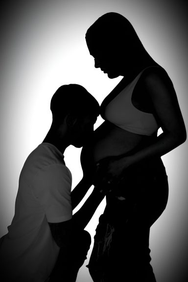 Silhouette maternity photo, dad kissing bump